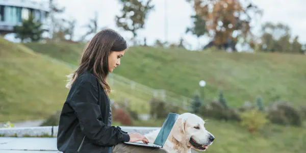 A Woman With A Laptop Computer And A Dog